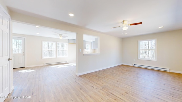 spare room with a baseboard radiator, a healthy amount of sunlight, and light wood-style flooring