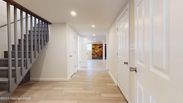 corridor with light wood-type flooring, stairway, baseboards, and recessed lighting