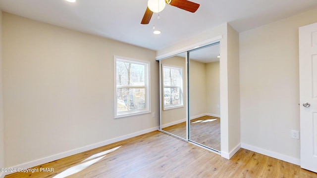 unfurnished bedroom featuring light wood finished floors, a ceiling fan, baseboards, and a closet