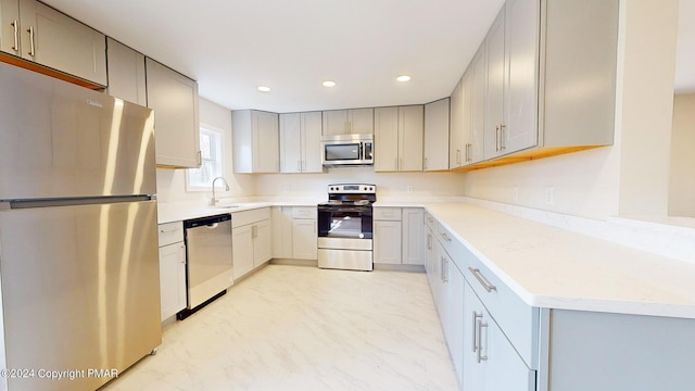 kitchen with recessed lighting, a sink, light countertops, appliances with stainless steel finishes, and gray cabinets