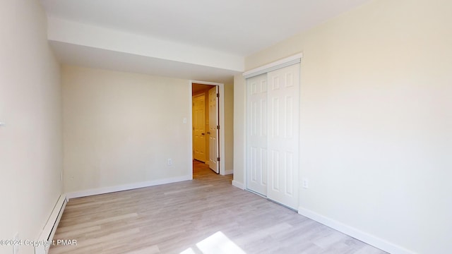 empty room with light wood finished floors, baseboards, and baseboard heating