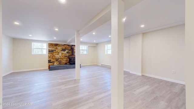 basement with a baseboard radiator, baseboards, and light wood-style flooring