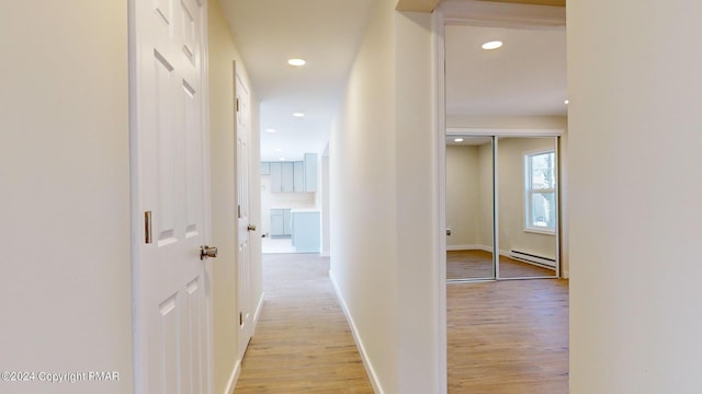 corridor featuring a baseboard heating unit, light wood-type flooring, baseboards, and recessed lighting