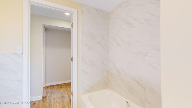 full bath with bathing tub / shower combination, baseboards, and wood finished floors