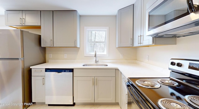 kitchen featuring gray cabinets, stainless steel appliances, a sink, and light countertops