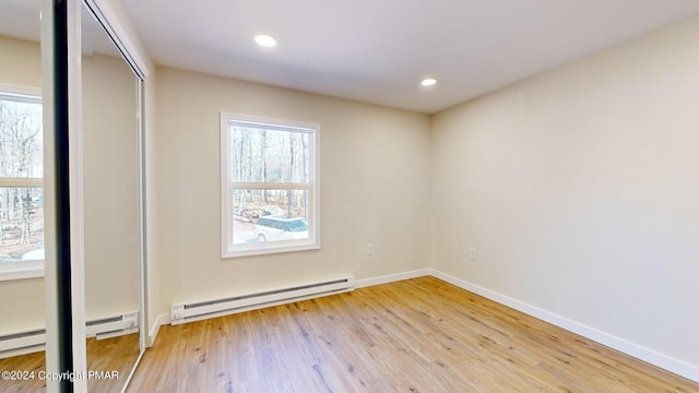 unfurnished room with a baseboard heating unit, baseboards, light wood-style flooring, and recessed lighting