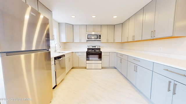 kitchen with stainless steel appliances, gray cabinets, light countertops, and a sink