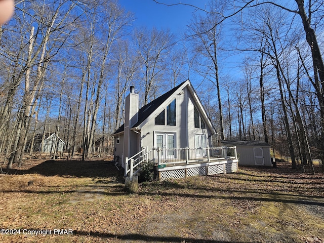 chalet / cabin featuring a storage unit, a deck, a chimney, and an outdoor structure