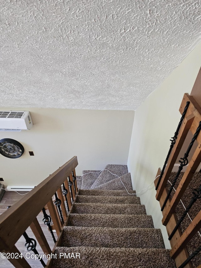 staircase with a textured ceiling and a wall mounted air conditioner