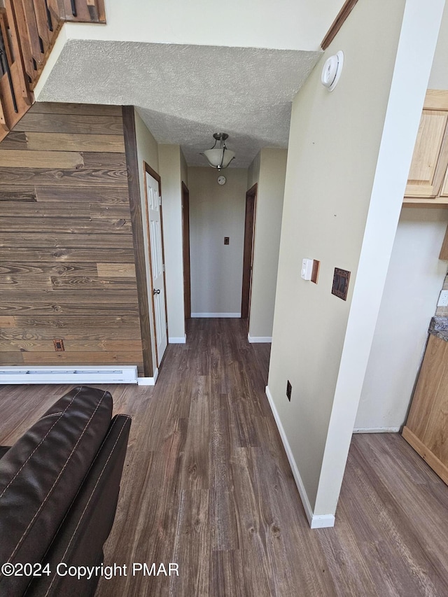 corridor with baseboards, a textured ceiling, and dark wood-style flooring