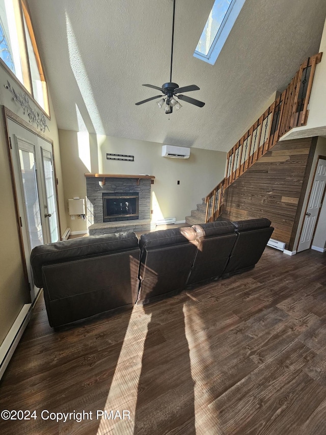 living area featuring a stone fireplace, a wall unit AC, wood finished floors, and ceiling fan