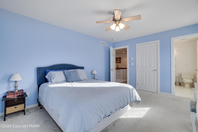 carpeted bedroom featuring a ceiling fan, ensuite bath, visible vents, and baseboards