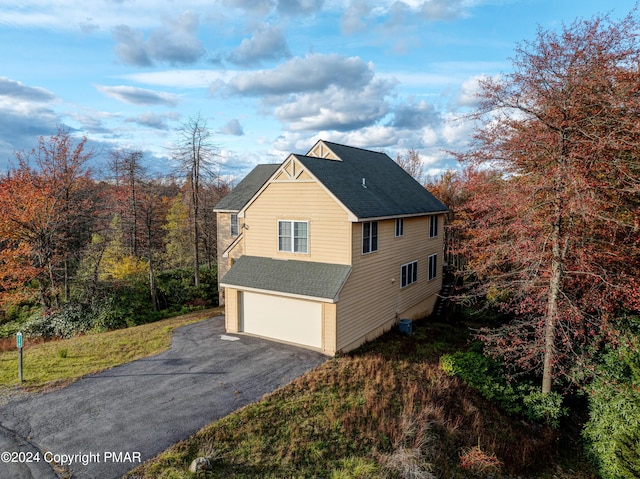 view of property exterior with central air condition unit, a shingled roof, and aphalt driveway