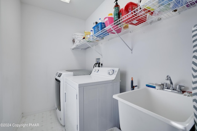 washroom with laundry area, baseboards, light floors, washing machine and dryer, and a sink