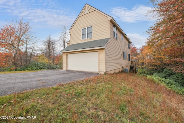 view of side of home featuring aphalt driveway, roof with shingles, and an attached garage