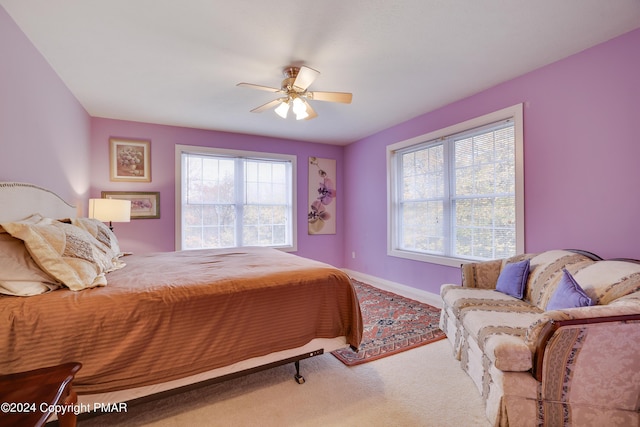 carpeted bedroom featuring multiple windows, baseboards, and a ceiling fan