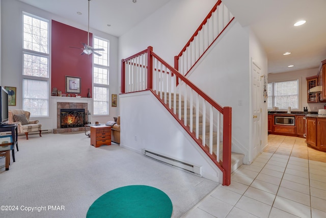 stairway with a baseboard radiator, a wealth of natural light, and a ceiling fan