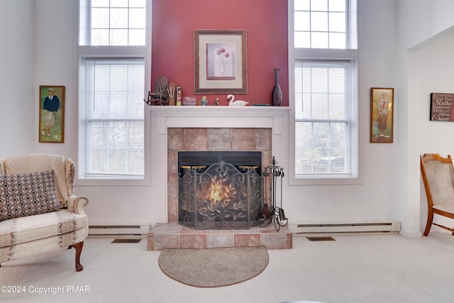 carpeted living area featuring a baseboard heating unit, baseboard heating, and a tiled fireplace