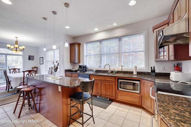 kitchen with brown cabinetry, a kitchen island, stainless steel microwave, a kitchen bar, and a sink