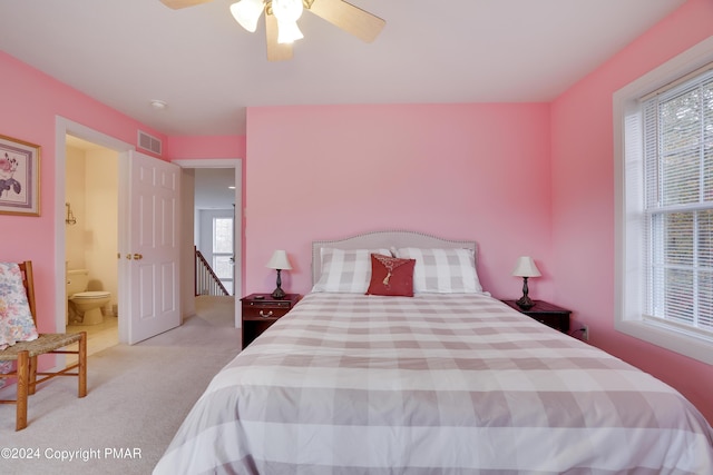 carpeted bedroom with ceiling fan, multiple windows, ensuite bath, and visible vents