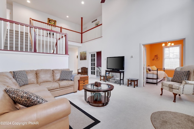 carpeted living room featuring a high ceiling, a notable chandelier, and recessed lighting