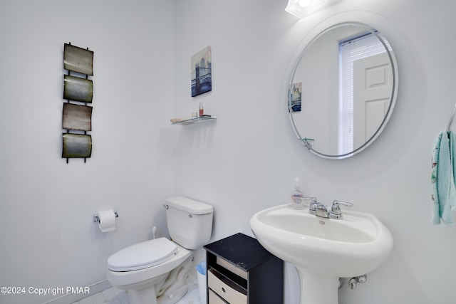 half bathroom with baseboards, a sink, and toilet