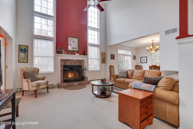 carpeted living area featuring a towering ceiling, ceiling fan with notable chandelier, visible vents, and a tile fireplace