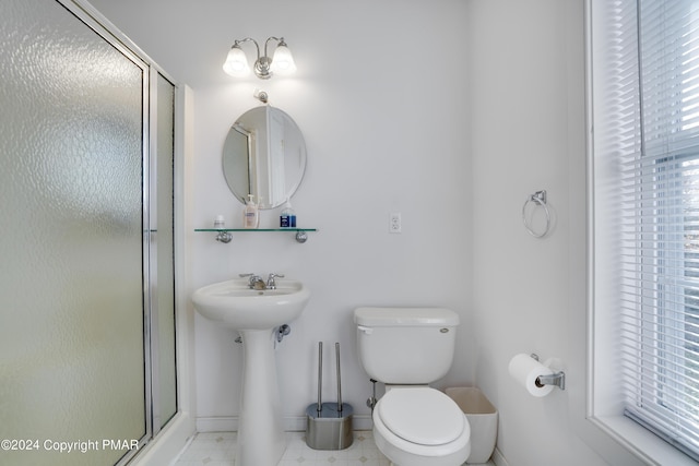 bathroom featuring a stall shower, toilet, and baseboards