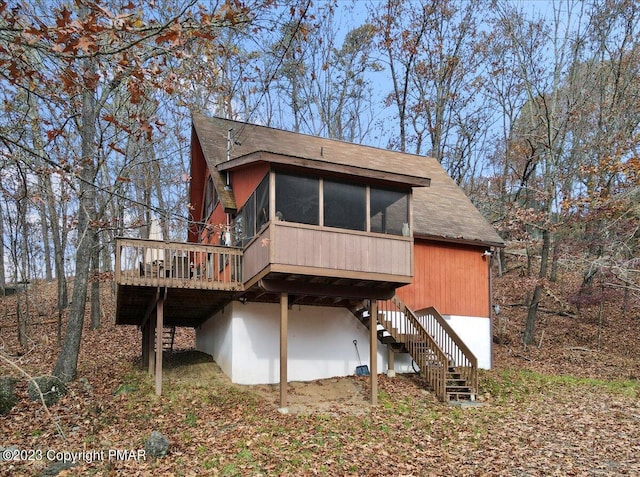 rear view of house with a sunroom, a deck, and stairs