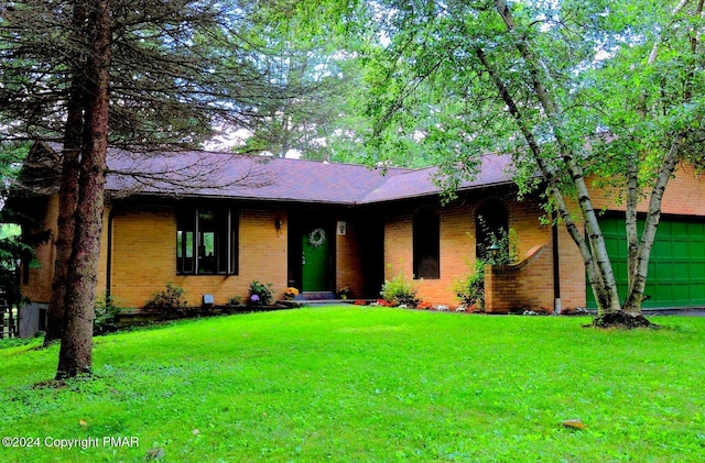 ranch-style home with a garage, brick siding, a front yard, and a shingled roof