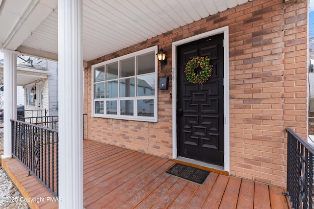 entrance to property with covered porch and brick siding