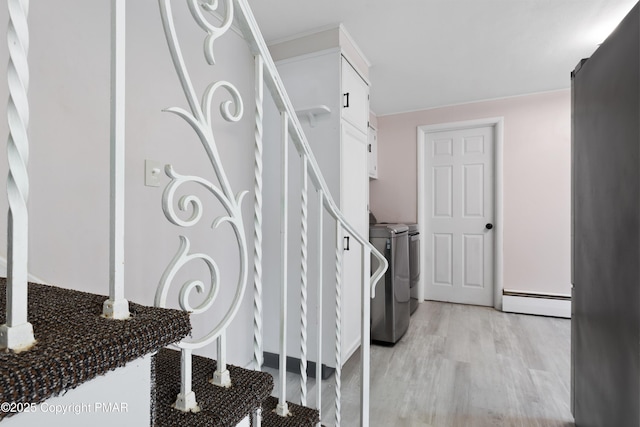 interior space with washer and dryer, baseboard heating, and wood finished floors