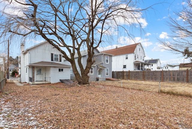 rear view of property featuring a chimney, a residential view, and fence