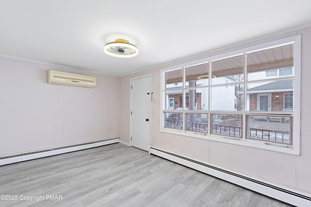 spare room with a wall unit AC, light wood finished floors, baseboard heating, and crown molding