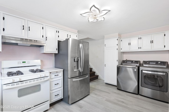 kitchen with under cabinet range hood, white cabinets, independent washer and dryer, white gas range, and stainless steel fridge