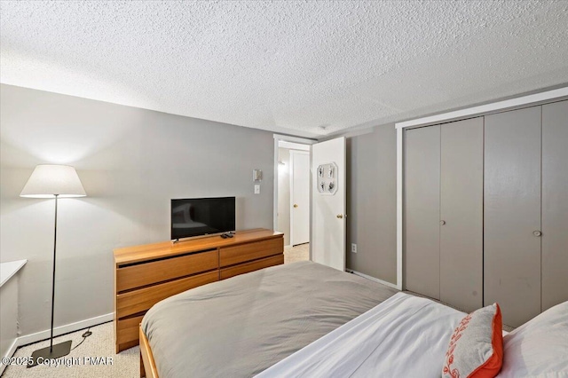 bedroom with a closet, light carpet, a textured ceiling, and baseboards