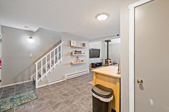 kitchen featuring a wood stove, baseboards, baseboard heating, and a textured ceiling