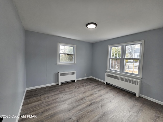 unfurnished room featuring baseboards, wood finished floors, and radiator