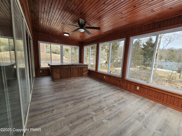 unfurnished sunroom featuring wooden ceiling, a wealth of natural light, and a ceiling fan