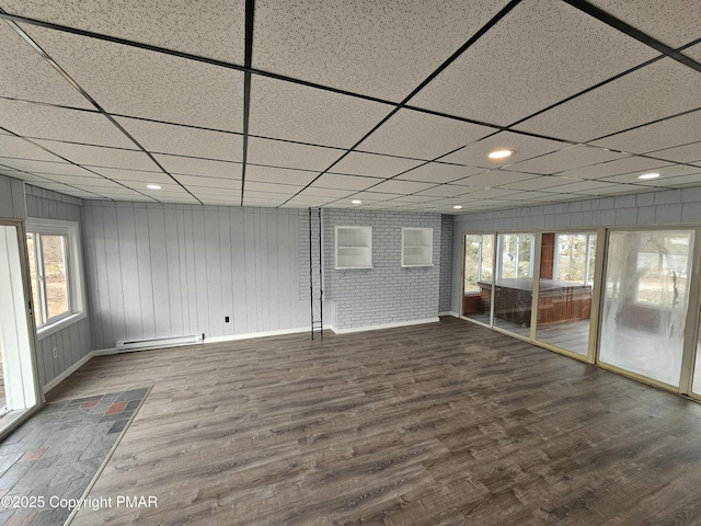 spare room with a drop ceiling, baseboards, baseboard heating, and wood finished floors