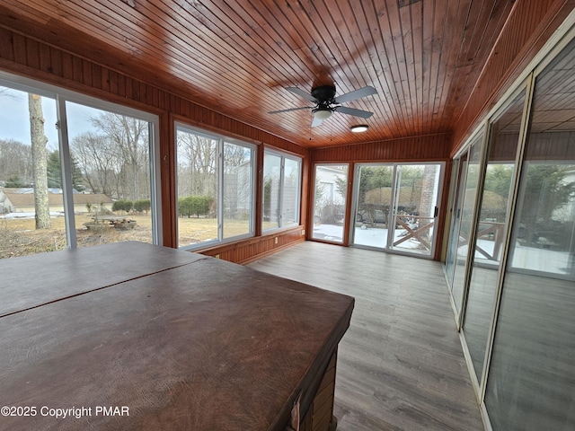 unfurnished sunroom with wood ceiling and a ceiling fan