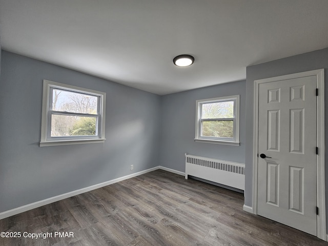 unfurnished bedroom featuring radiator, baseboards, and wood finished floors