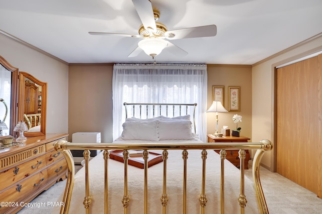 carpeted bedroom featuring ornamental molding, a closet, and ceiling fan