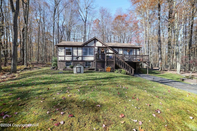 view of front of property featuring brick siding, a front lawn, driveway, a wooden deck, and stairs