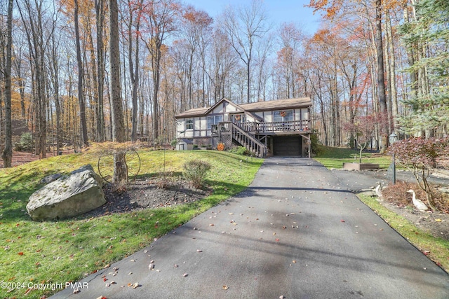 view of front of house with a garage, stairs, driveway, a wooden deck, and a front yard