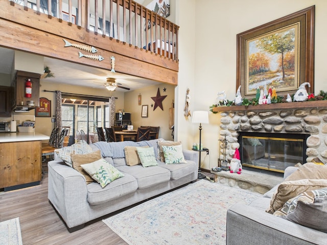 179 Choctaw Dr, Pocono Lake, PA 18347 - living area with wood finished floors, a towering ceiling, a ceiling fan, and a stone fireplace