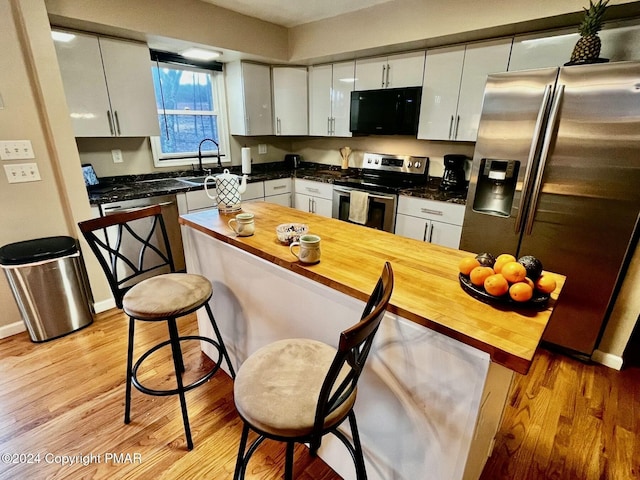 kitchen with appliances with stainless steel finishes, white cabinetry, and light wood finished floors