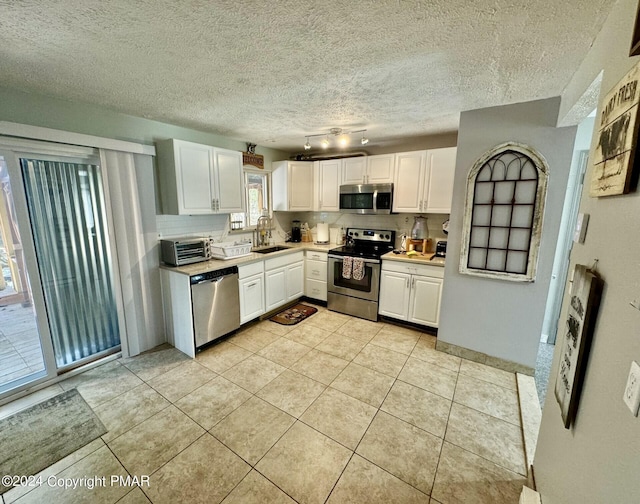 kitchen with a sink, appliances with stainless steel finishes, backsplash, and white cabinetry