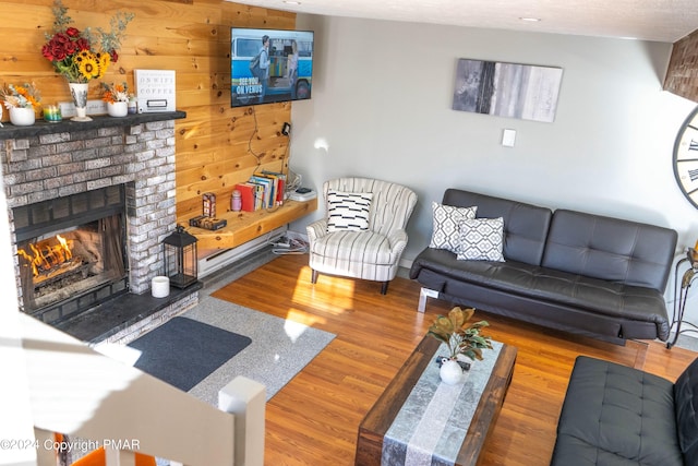 living room featuring wood finished floors, wooden walls, and a fireplace
