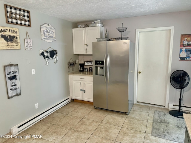 kitchen with light tile patterned flooring, a baseboard heating unit, white cabinets, and stainless steel fridge with ice dispenser
